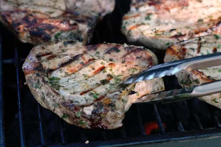 flipping grilled pork chops on a grill