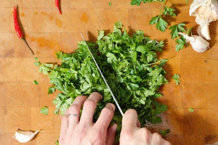 chopping a large amount of fresh parsley leaves