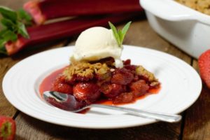 a portion of strawberry rhubarb crumble topped with vanilla icecream