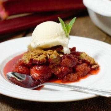 a portion of strawberry rhubarb crumble topped with vanilla icecream