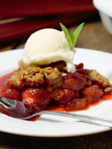 a portion of strawberry rhubarb crumble topped with vanilla icecream