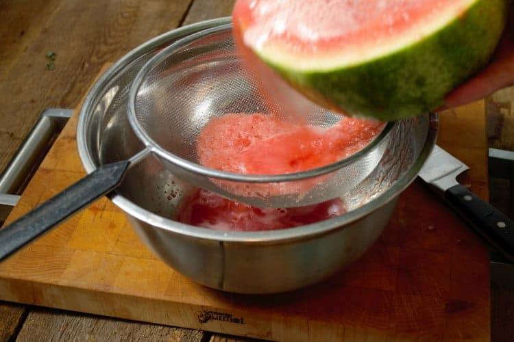 pouring the blended watermelon pulp and juice through a strainer