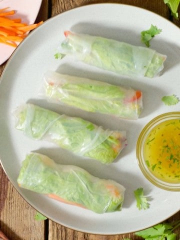 rice paper rolls arranged on a plate around a thai dipping sauce