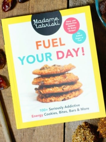 a copy of the cookbook 'Fuel Your Day!' by madame Labriski on a barn board tabletop surrounded by baked treats
