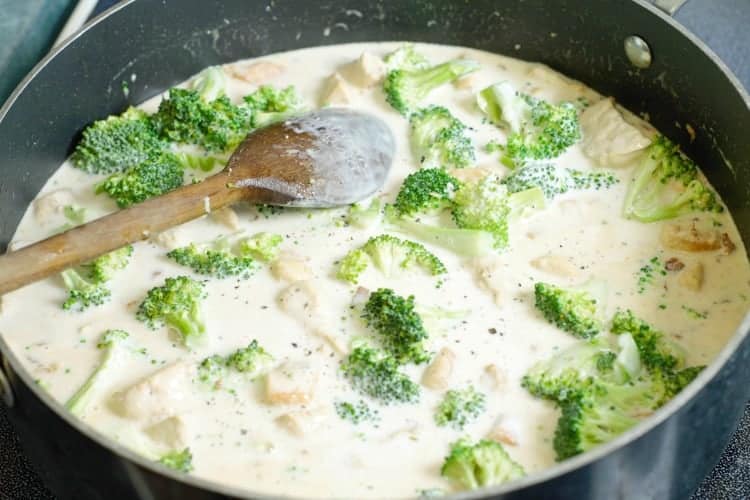 coconut milk added to a pan of broccoli, chicken and bacon