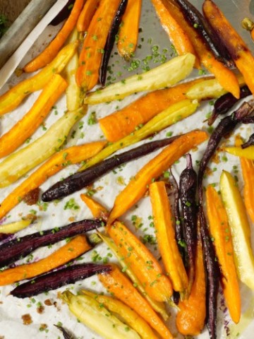 oven roasted baby carrots on a sheetpan garnished with chives