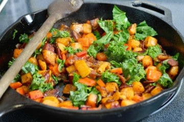 sauteed sweet potatoe, red bell pepper, kale, onion, and bacon in a cast iron pan