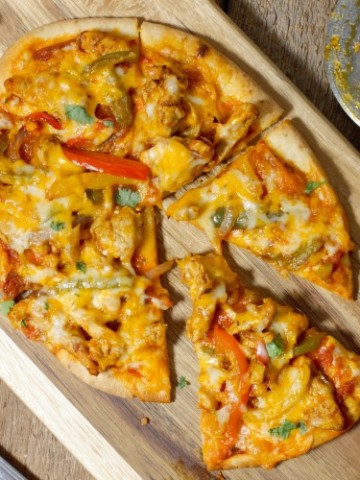 chicken fajita naan pizza cut and served on a wooden board