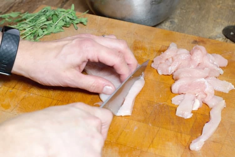 slicing a chicken breast into strips