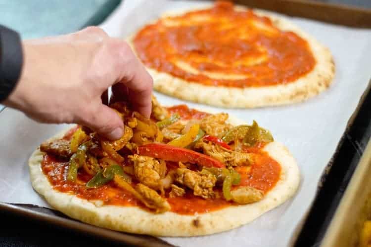 topping a naan pizza with chicken fajita mix