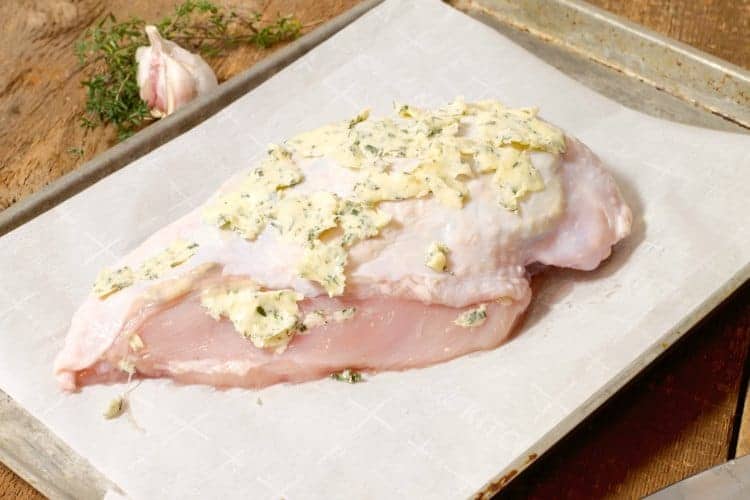 raw turkey breast covered in butter and herbs prior to roasting