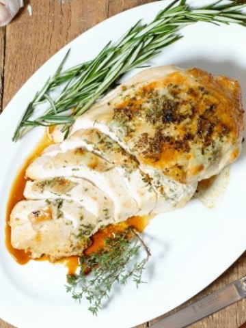 garlic and herb roast turkey breast sliced and served on a white platter