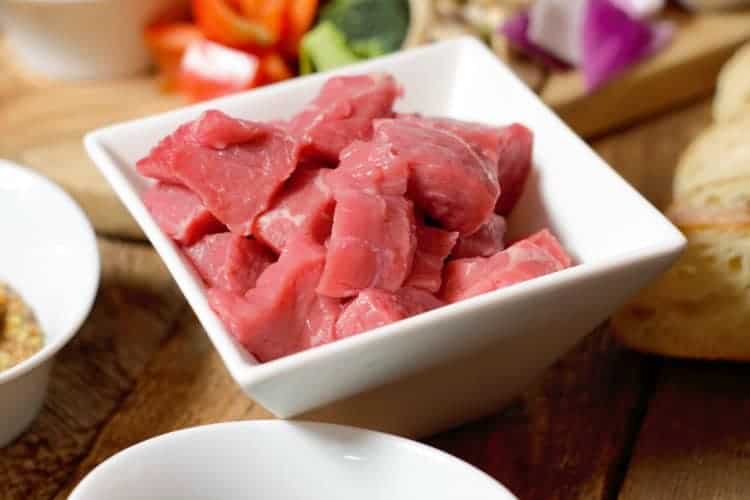 raw diced meat to be served fondue style in a white bowl