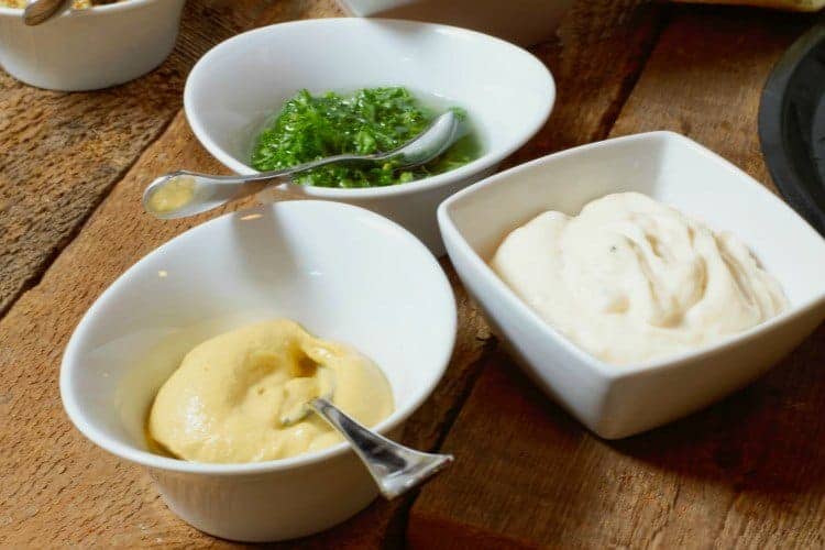 small white bowls filled with various condiments and dips