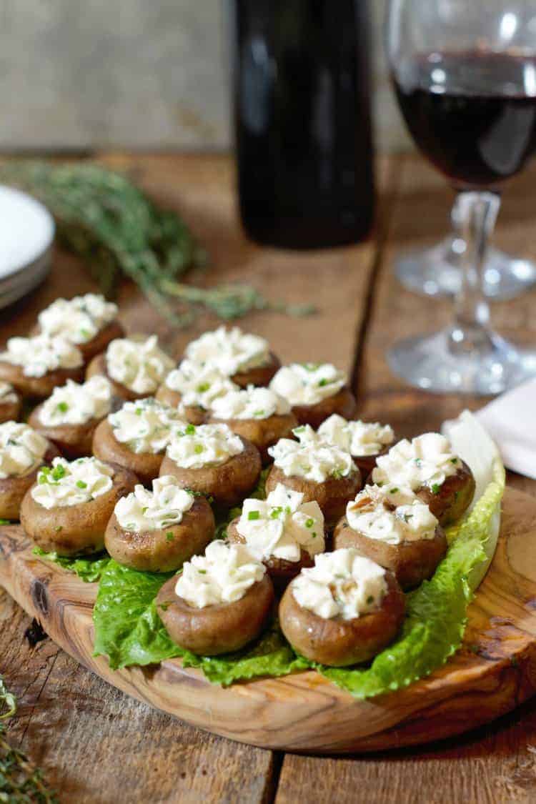 goat cheese stuffed mushroom caps displayed on a wooden serving board