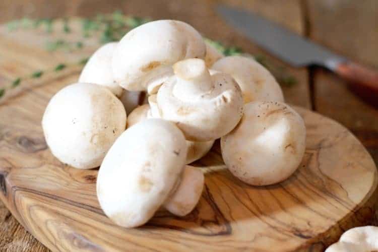white button mushrooms on a wooden board