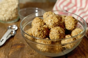 peanut butter protein balls in a glass bowl on a wood board tabletop