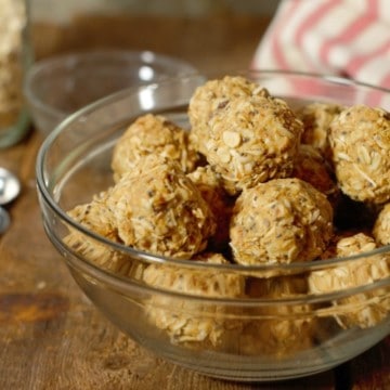 peanut butter protein balls in a glass bowl on a wood board tabletop