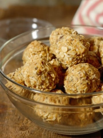 peanut butter protein balls in a glass bowl on a wood board tabletop