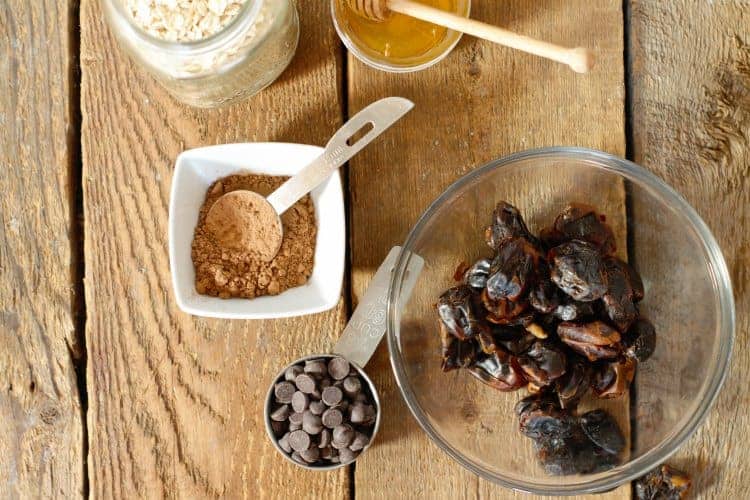 some of the ingredients needed to make chocolate date balls on a wood board background