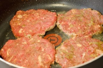 moose meat burgers cooking in a pan