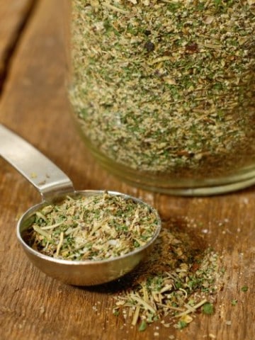 homemade italian seasoning in a measuring spoon on a wooden table