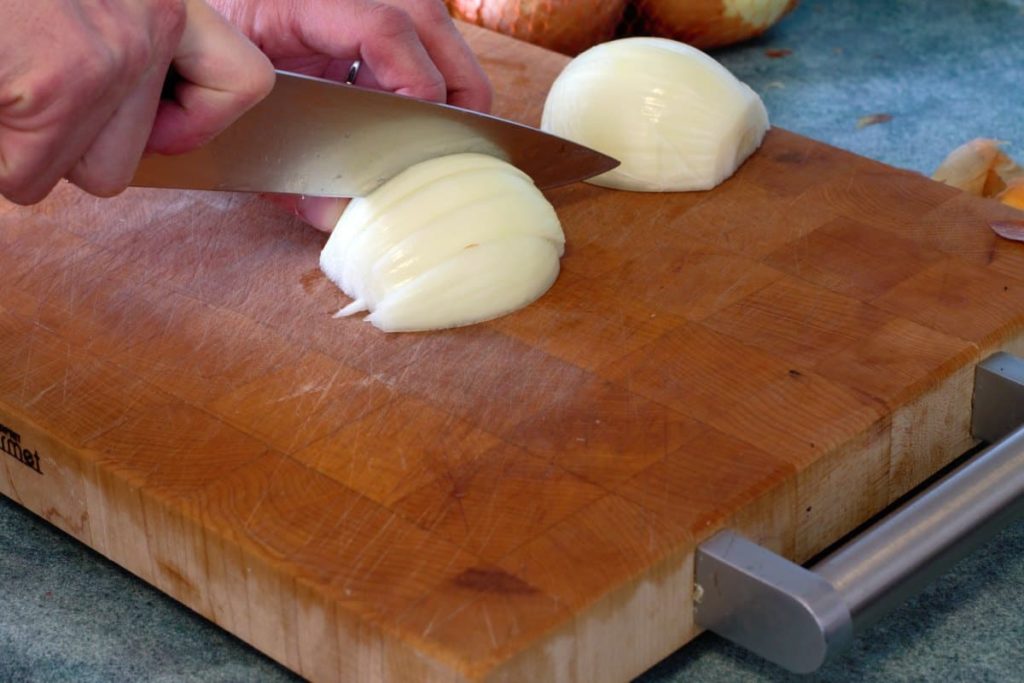 cutting a peeled onion into a julienne cut