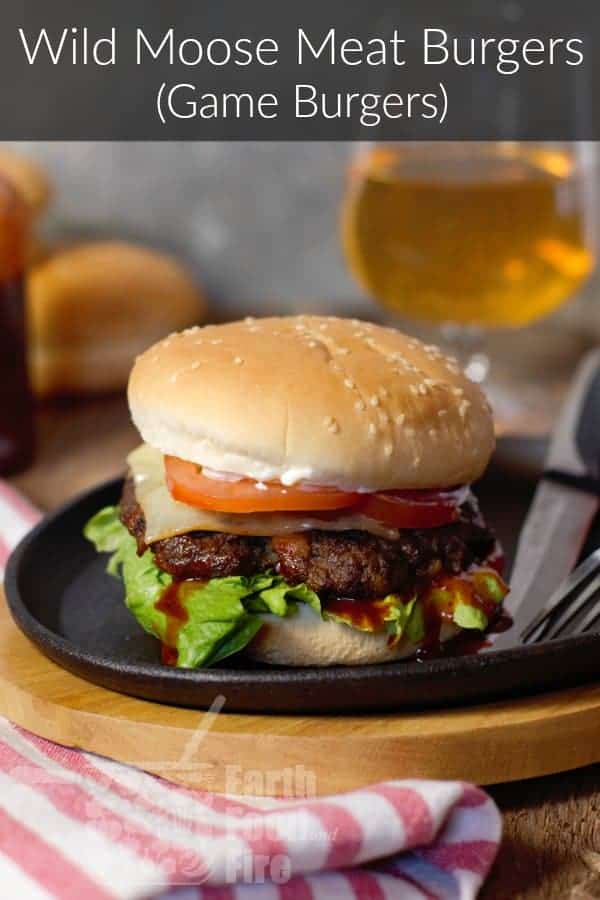 vertical image of a fully loaded moose meat burger on a cast iron serving platter