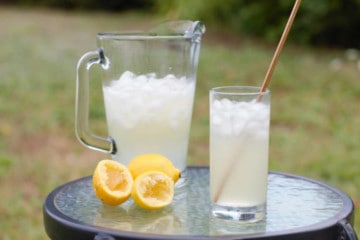 old fashioned lemonade served in a glass with a metal straw on a table outside