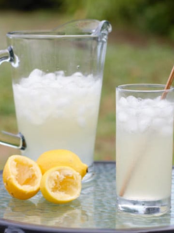 old fashioned lemonade served in a glass with a metal straw on a table outside