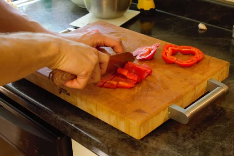 dicing red bell pepper on a wooden cutting board