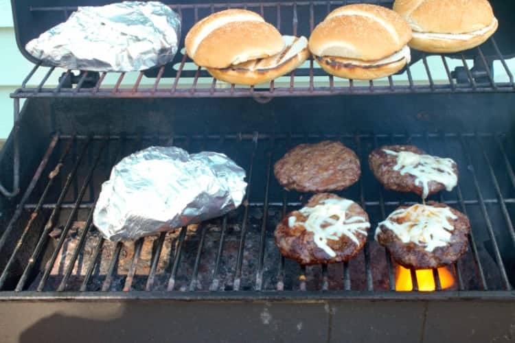 grilling tex mex burger patties, veggie foil pouch, and buns on the bbq