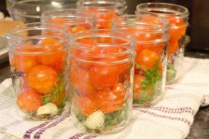 mason jars filled with spices and cherry tomatoes prior to pickling