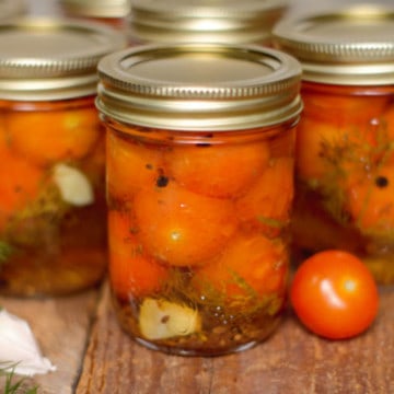 pickled cherry tomatoes in mason jars on a barn board backgound