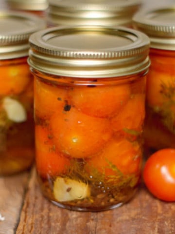 pickled cherry tomatoes in mason jars on a barn board backgound