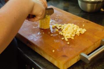 cutting raw corn kernels off the cob