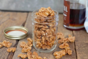 maple candied walnuts displayed in a glass mason jar on a barnboard tabletop