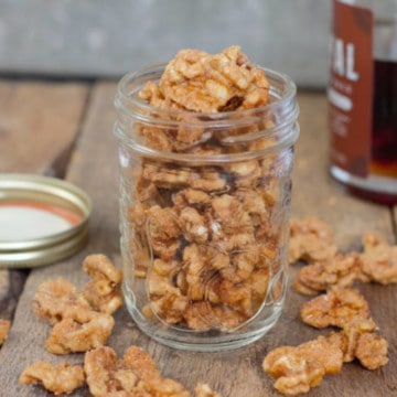 maple candied walnuts displayed in a glass mason jar on a barnboard tabletop
