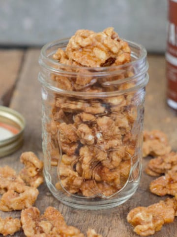 maple candied walnuts displayed in a glass mason jar on a barnboard tabletop