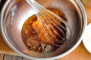 pumpkin puree, maple syrup, and various spices in a stainless steel bowl