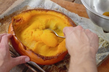 scooping cooked pumpkin flesh out of the skin