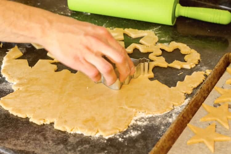 cutting out festive cookie shapes with cookie cutters