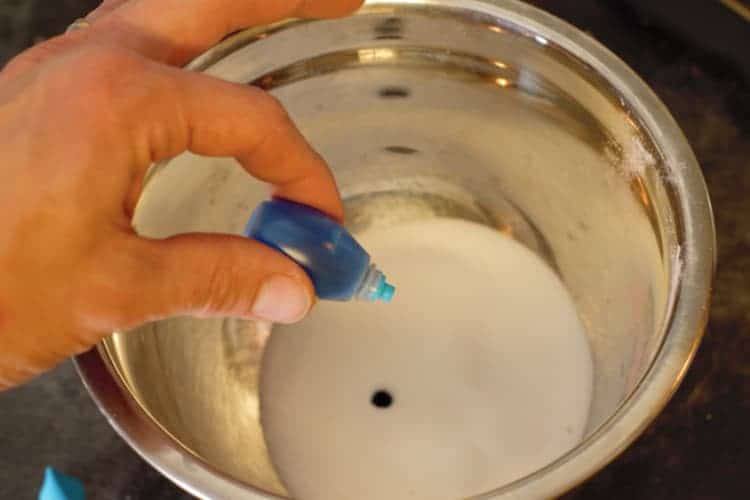 adding a drop of blue food coloring to white sugar