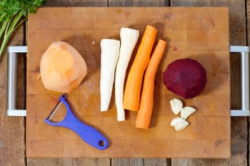 various root vegetables peeled on a wooden cutting board