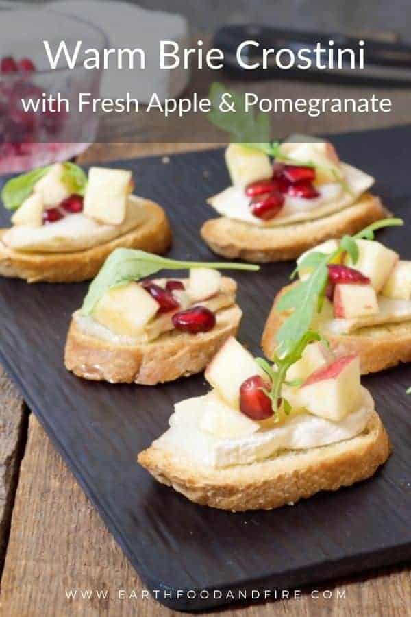 wam brie crostini topped with a fresh apple and pomegranate salad served on a slate serving tray
