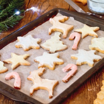 simple festive sugar cookies on a baking tray on a rustic wooden counter.