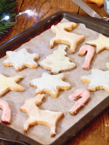 simple festive sugar cookies on a baking tray on a rustic wooden counter.