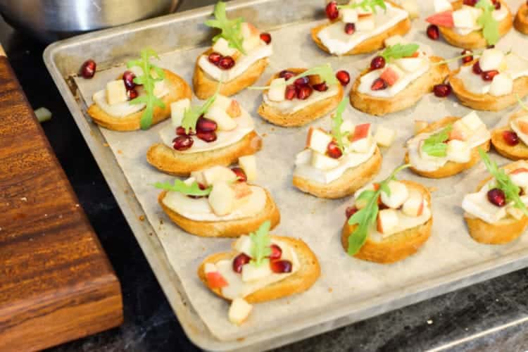 fully garnished warm brie crostini's on a sheet pan ready to be served