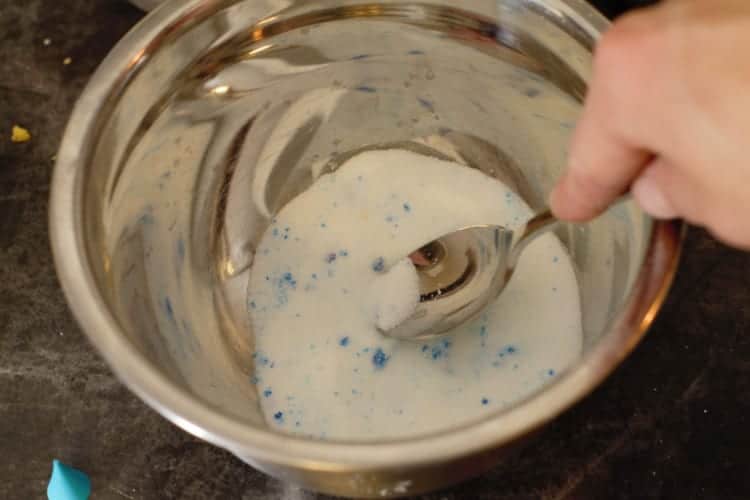 mixing the blue food coloring into the sugar with a spoon