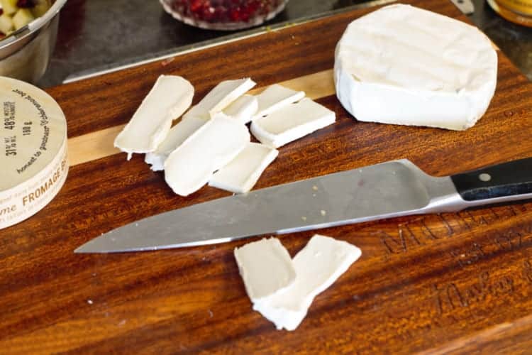brie cut into thin slices on a wooden cutting board